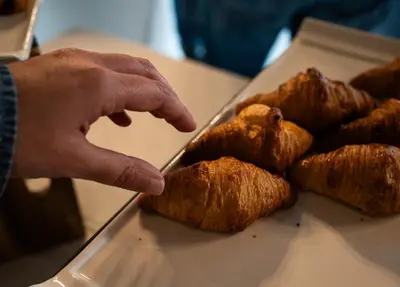 a person pointing at a pile of pastries on a table at Pazo Arretén in Padrón