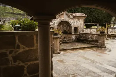 an outdoor patio with an arch and a stone building at Pazo Arretén in Padrón
