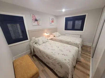 two beds in a small room with two windows at Casa Mateo in Allariz
