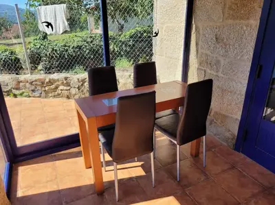 a wooden table with four chairs in front of a window at Casa Mateo in Allariz