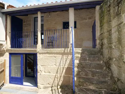a stone house with a blue door and stairs at Casa Mateo in Allariz