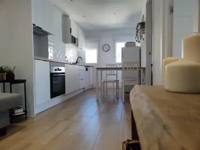 a kitchen with white cabinets and a table and chairs at Apartamento La Ribera in Betanzos