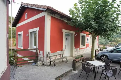 a red and white house with a table and chairs at Apartamentos Bágoas de Mencía Peares Ribeira Sacra in Carballedo