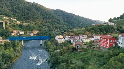 a blue train on a bridge over a river at Apartamentos Bágoas de Mencía Peares Ribeira Sacra in Carballedo