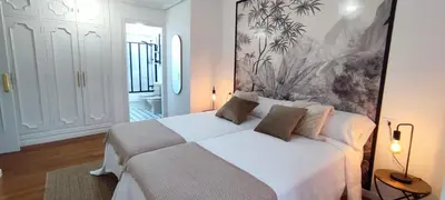 a bedroom with a white bed and a painting on the wall at Home Ourense Miño in Ourense