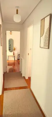 a hallway with a white wall and a rug at Home Ourense Miño in Ourense