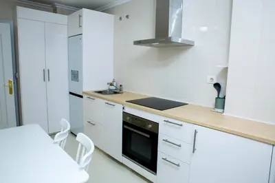 a kitchen with white cabinets and a stove top oven at Home Ourense Miño in Ourense