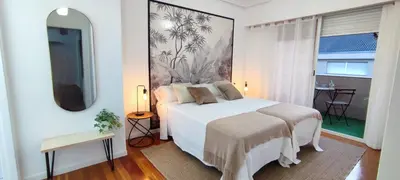 a bedroom with a white bed and a large painting on the wall at Home Ourense Miño in Ourense