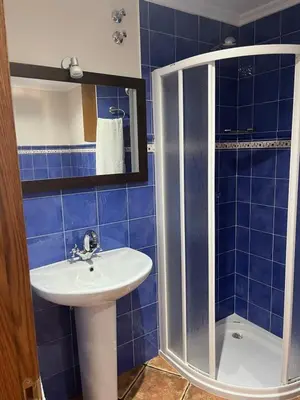 a blue tiled bathroom with a sink and a shower at A Xanuca in Taramundi