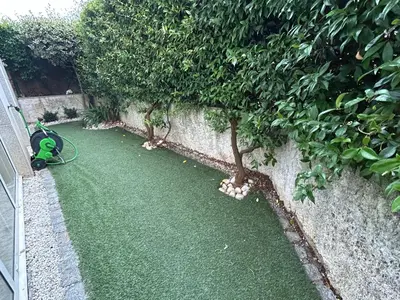 a garden with two trees next to a wall at Mar y Playa con Jardín in A Coruña