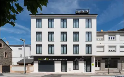 a white building with black windows on a street at Duerming Avenida 85 Burela VUT in Burela de Cabo