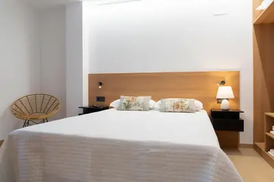 a bedroom with a white bed and a chair at Duerming Avenida 85 Burela VUT in Burela de Cabo