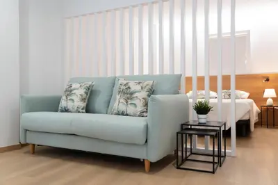 a living room with a blue couch and a bed at Duerming Avenida 85 Burela VUT in Burela de Cabo