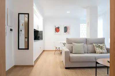a white living room with a couch and a mirror at Duerming Avenida 85 Burela VUT in Burela de Cabo