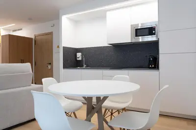 a white kitchen with a white table and chairs at Duerming Avenida 85 Burela VUT in Burela de Cabo