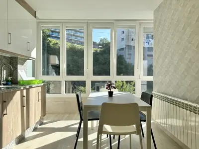 a kitchen with a white table and chairs and windows at Front Beach I in Sada