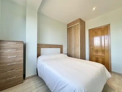 a bedroom with a white bed and a wooden cabinet at Front Beach I in Sada