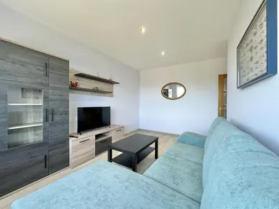 a living room with a blue couch and a tv at Front Beach I in Sada