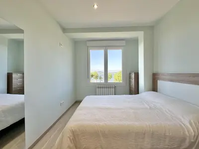 a white bedroom with a large bed and a window at Front Beach I in Sada