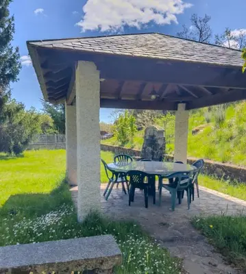a patio with a table and chairs under a pavilion at Casa Rural LOS MILLARES in Ribadelago