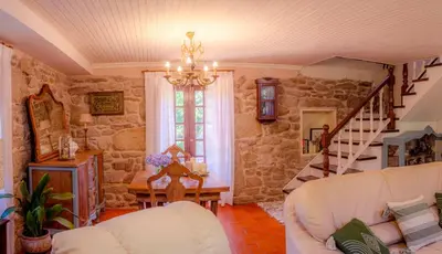 a living room with stone walls and a chandelier at Casa rural Catro do Lugarexo in Villarmayor