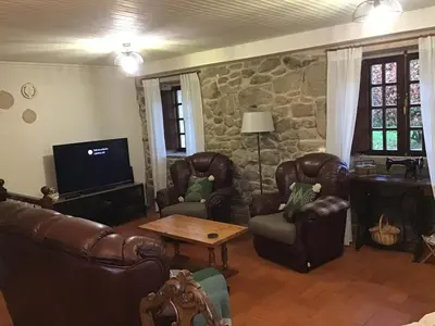 a living room with leather furniture and a stone wall at Casa rural Catro do Lugarexo in Villarmayor