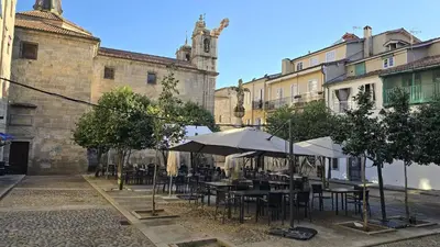an outdoor cafe with tables and umbrellas in front of a building at Calpurnia Abana in Ourense