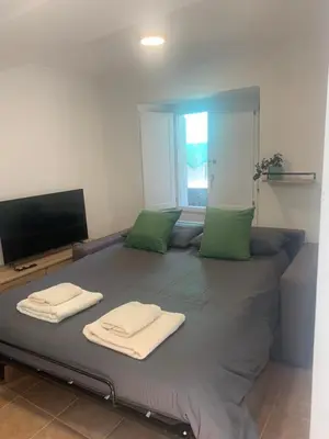 a large bed with green pillows and a television at A Casa do Sastre1 in Ribadavia