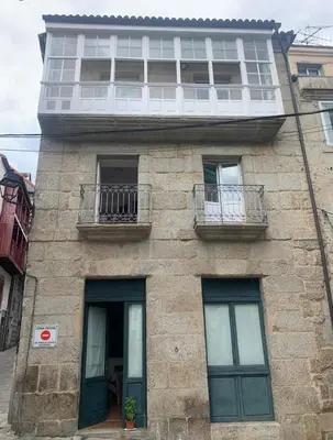 a stone building with two windows and a balcony at A Casa do Sastre1 in Ribadavia