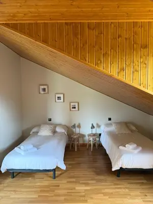 two beds in a room with wooden ceilings at La casa de Canedo in Arganza