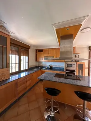 a kitchen with wooden cabinets and a island with bar stools at La casa de Canedo in Arganza