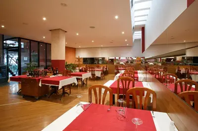 a restaurant with tables and chairs with red tablecloths at Hotel Restaurante Pontiñas in Lalín