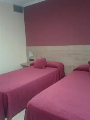 two beds in a room with pink sheets at Hotel Restaurante Pontiñas in Lalín