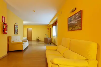 a yellow living room with a couch and a chair at Hotel Restaurante Pontiñas in Lalín