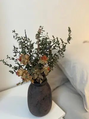 a vase with flowers on a table next to a bed at As Travesas II in Betanzos