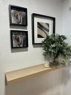 a shelf with three pictures and a vase with a plant at As Travesas II in Betanzos
