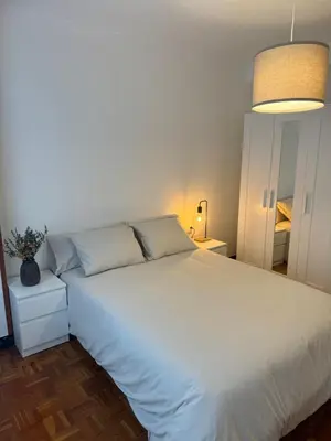 a bedroom with a large white bed and a lamp at As Travesas II in Betanzos