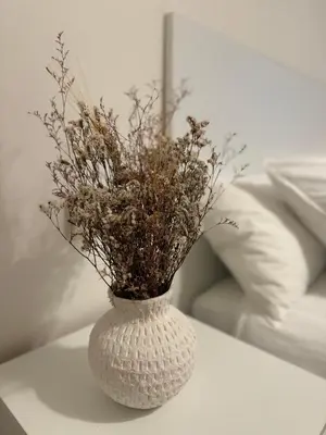 a white vase filled with dried flowers on a table at As Travesas II in Betanzos