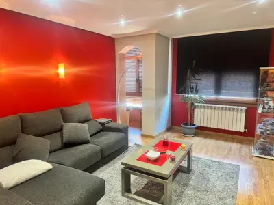 a living room with a couch and a red wall at El rincón de Emilio in Monforte de Lemos