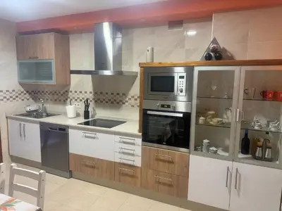 a kitchen with stainless steel appliances and wooden cabinets at El rincón de Emilio in Monforte de Lemos