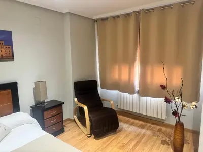 a bedroom with a chair and a window at El rincón de Emilio in Monforte de Lemos