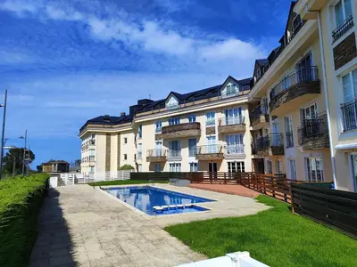 a large building with a swimming pool in front of it at Apartamento Atico Lúa As Catedrais in San Miguel de Reinante