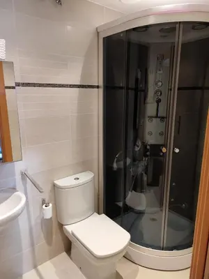 a bathroom with a toilet and a glass shower at Apartamento Atico Lúa As Catedrais in San Miguel de Reinante