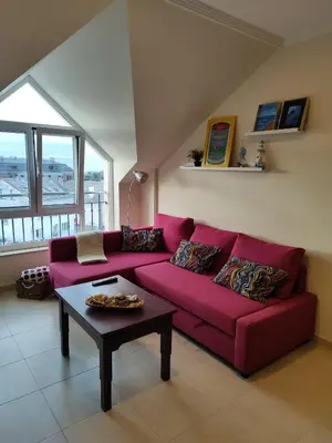 a living room with a red couch and a table at Apartamento Atico Lúa As Catedrais in San Miguel de Reinante