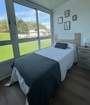 a bedroom with a bed and a large window at PortoHome Ático in Portomarin