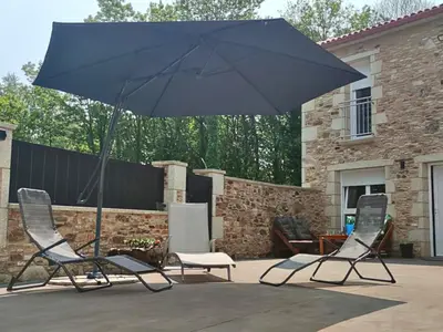 two chairs and an umbrella on a patio at Vivienda de uso Turístico Casa As Cachopas in Palas de Rei