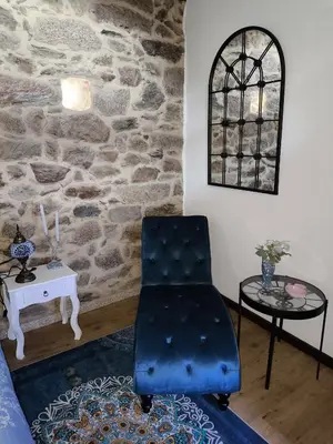 a blue chair in a room with a stone wall at Xiravai-Ribeira Sacra in Peares