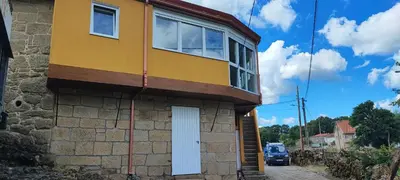 a yellow house with a white door on a building at Casa do Outeiro de Aguil in Castro Caldelas