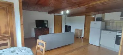 a living room with a white refrigerator and a kitchen at Casa do Outeiro de Aguil in Castro Caldelas