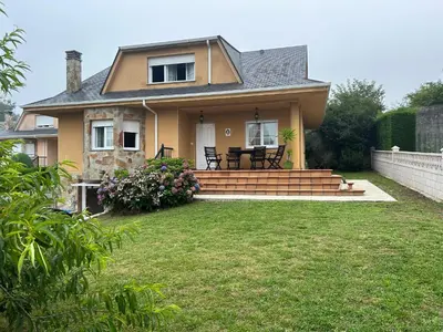 a house with a patio and a grass yard at Preciosa casa en A Caridad in La Caridad